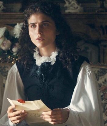 Eugenia – LezWatch.TV Woman in period clothing reads a letter with a red wax seal, seated indoors with a vintage backdrop.