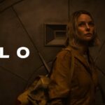 Poster for Silo (Apple TV+): a woman with a backpack in a dim, industrial setting with the title 'SILO' visible.