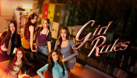 Group of young women posing together in a stylish room with 'Girl Rules' text on a glass wall behind them.